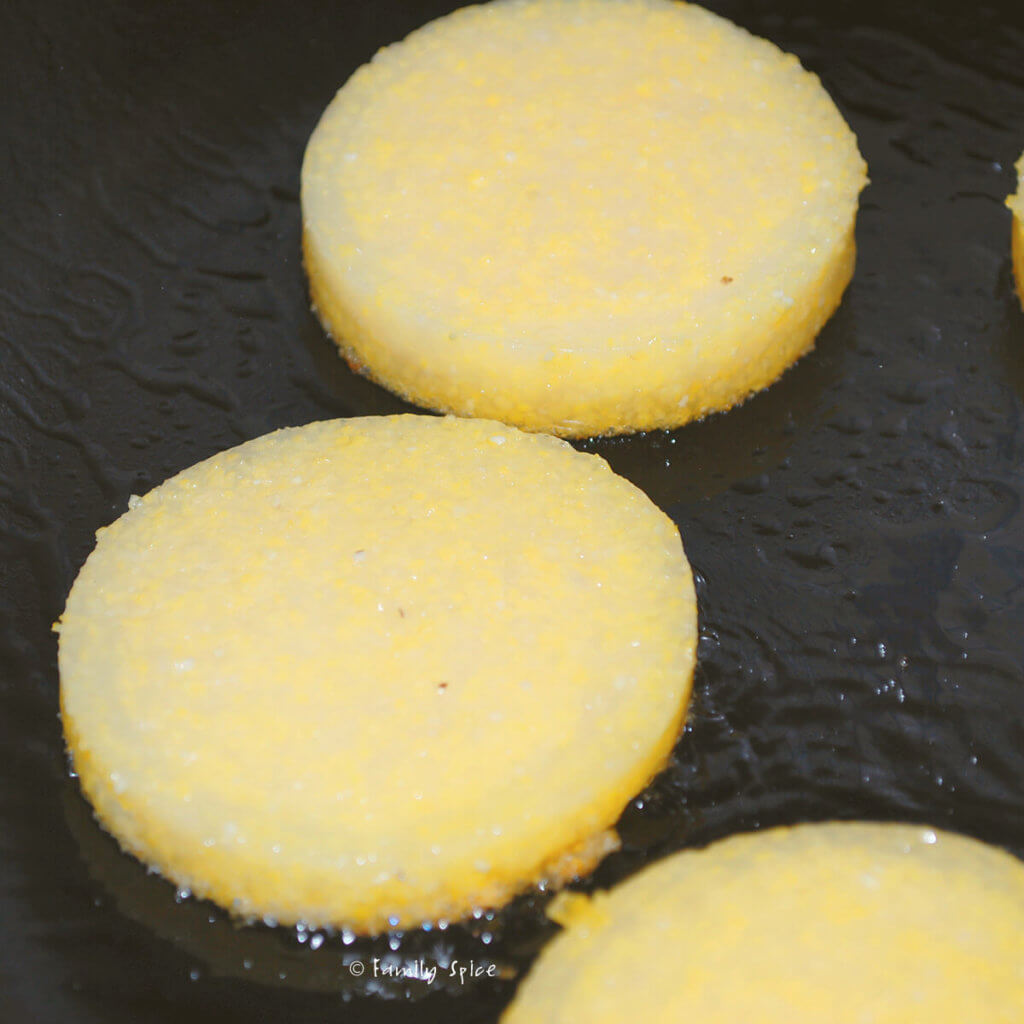 Polenta rounds getting browned in a cast iron pan