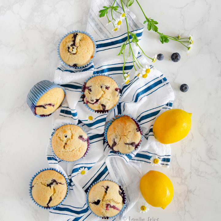 Overhead view of several lemon blueberry muffins on a blue striped dish towel with two lemons