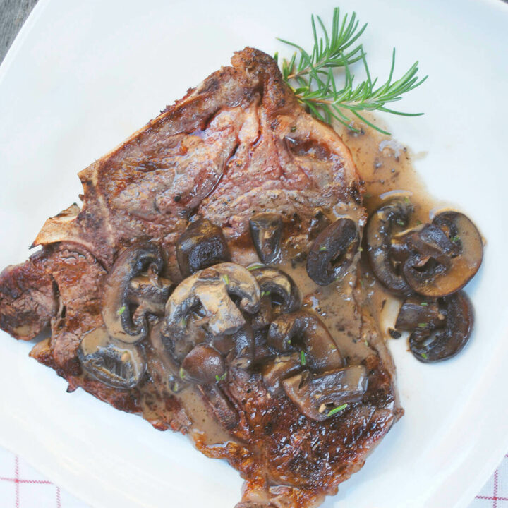 Grilled T-Bone with Creamy Mushroom Sauce on a white plate