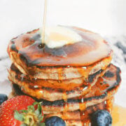 A stack of pancakes with syrup poured on it