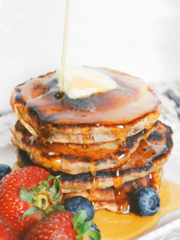 A stack of pancakes with syrup poured on it