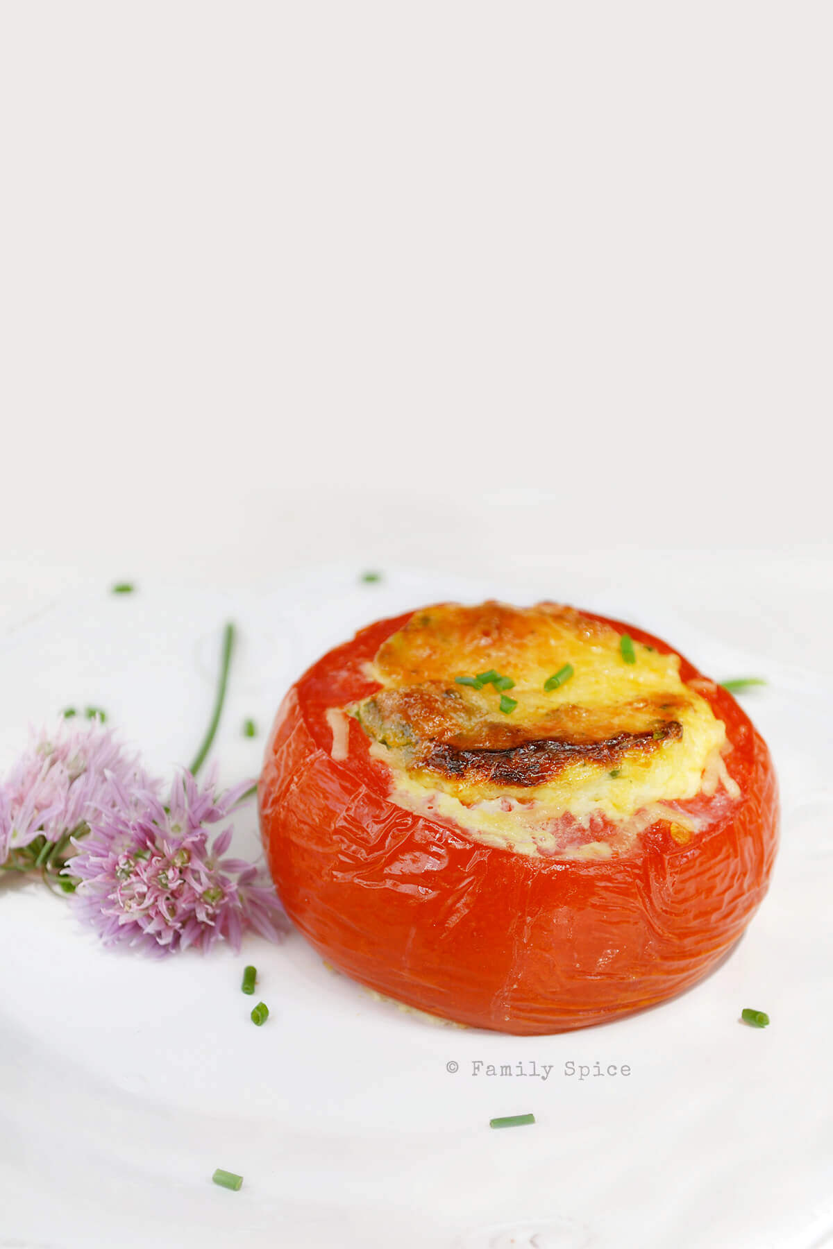 Eggs baked in whole tomatoes and topped with cheese and chives