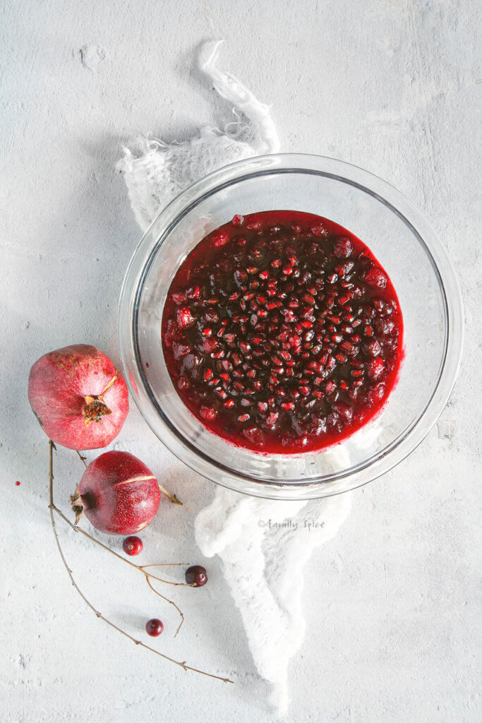 Cranberry Pomegranate Sauce in a glass bowl with fresh pomegranate arils sprinkled over it