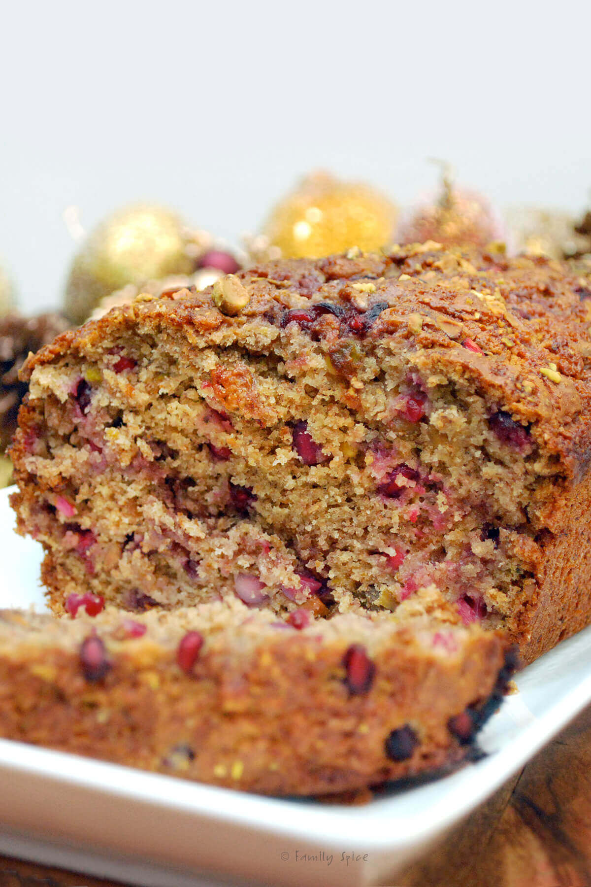 A loaf of pomegranate banana bread with a slice cut off