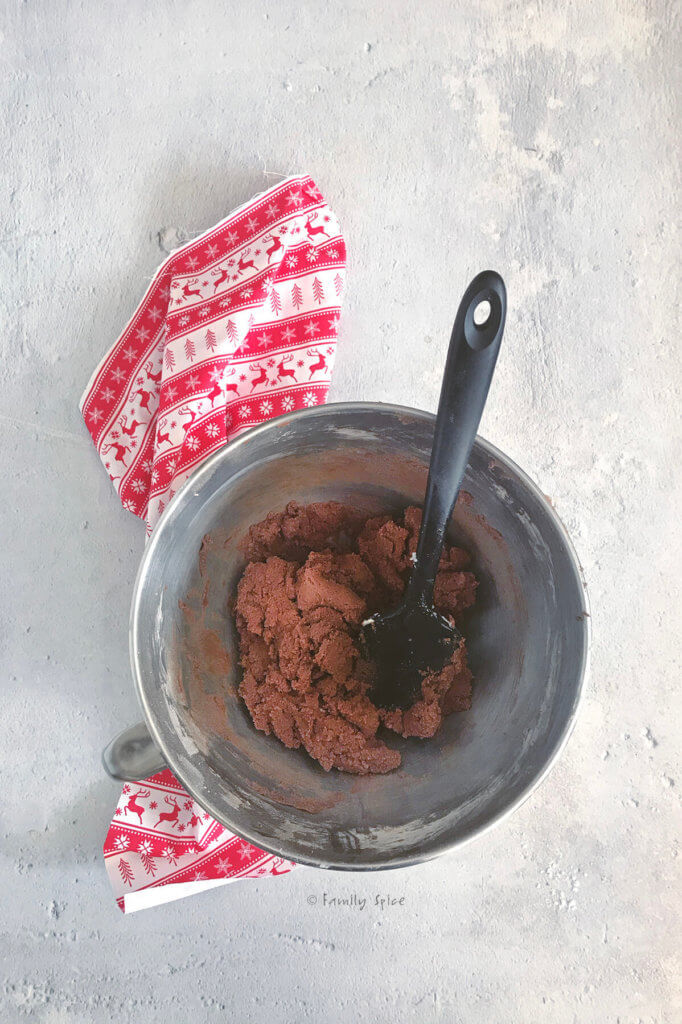 Chocolate cookie dough in a mixing bowl with a rubber scraper