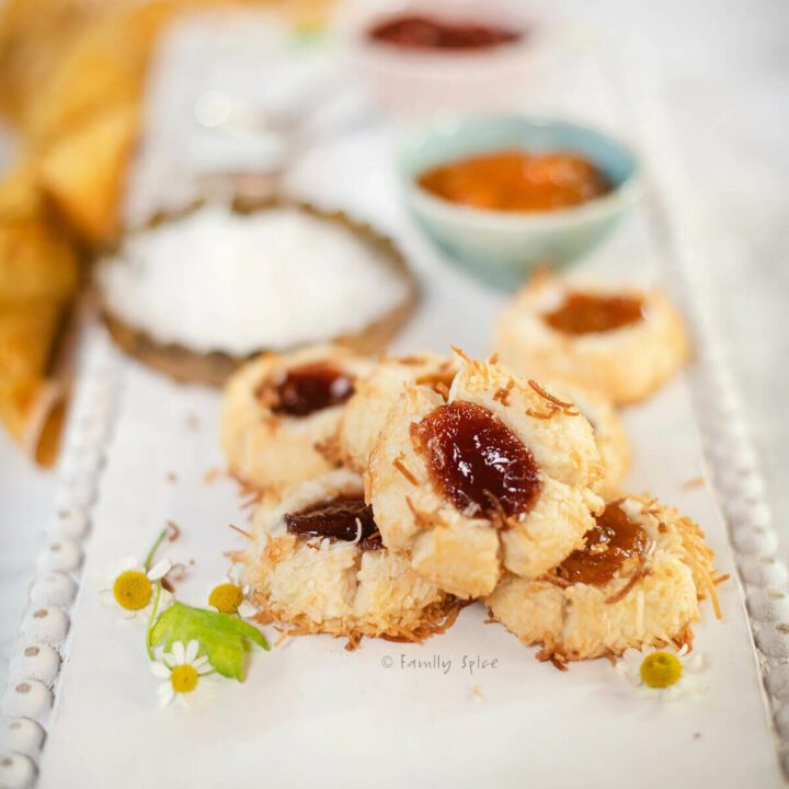 Closeup of coconut jam thumbprint cookies on a white board