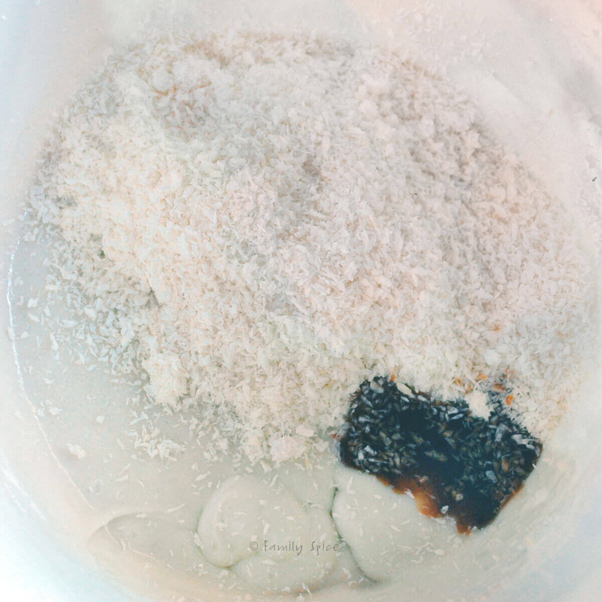 A white mixing bowl with ingredients to make coconut thin cookies