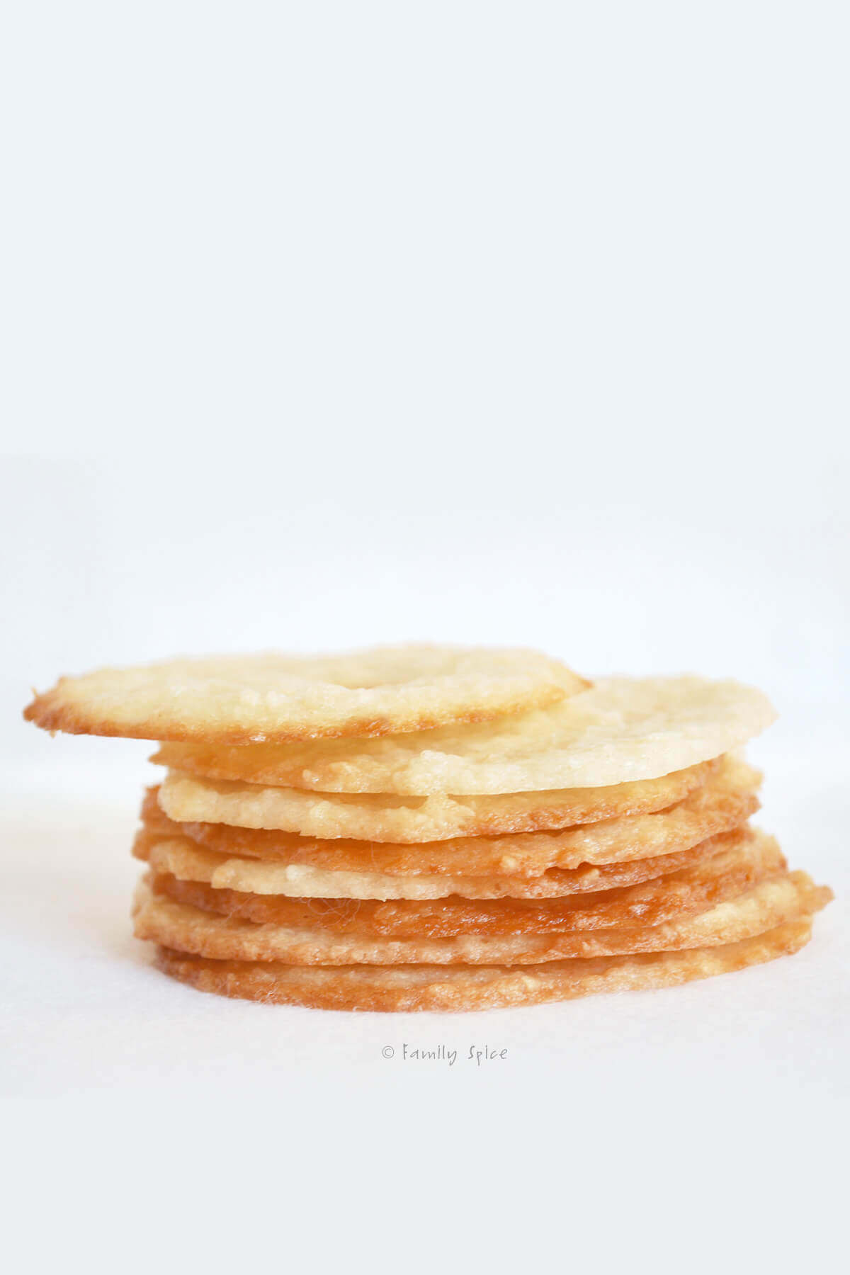Side view showing a stack of coconut thin cookies on a white surface