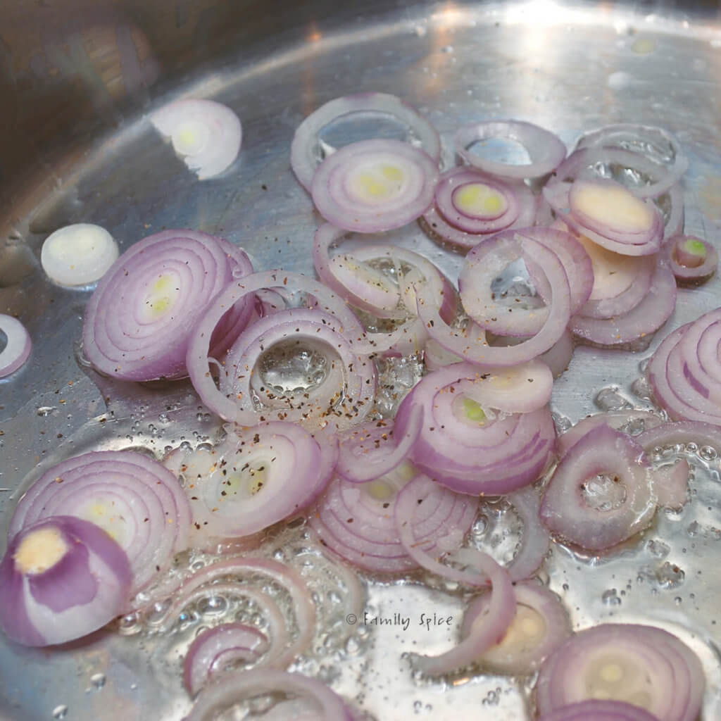 Sliced shallots getting browned in a pot with hot oil