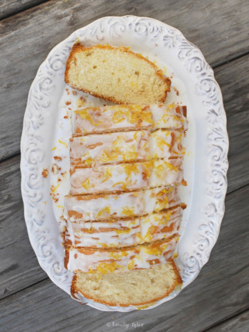 Top view of a loaf of lemon tea cake cut into slices onto a white oval platter