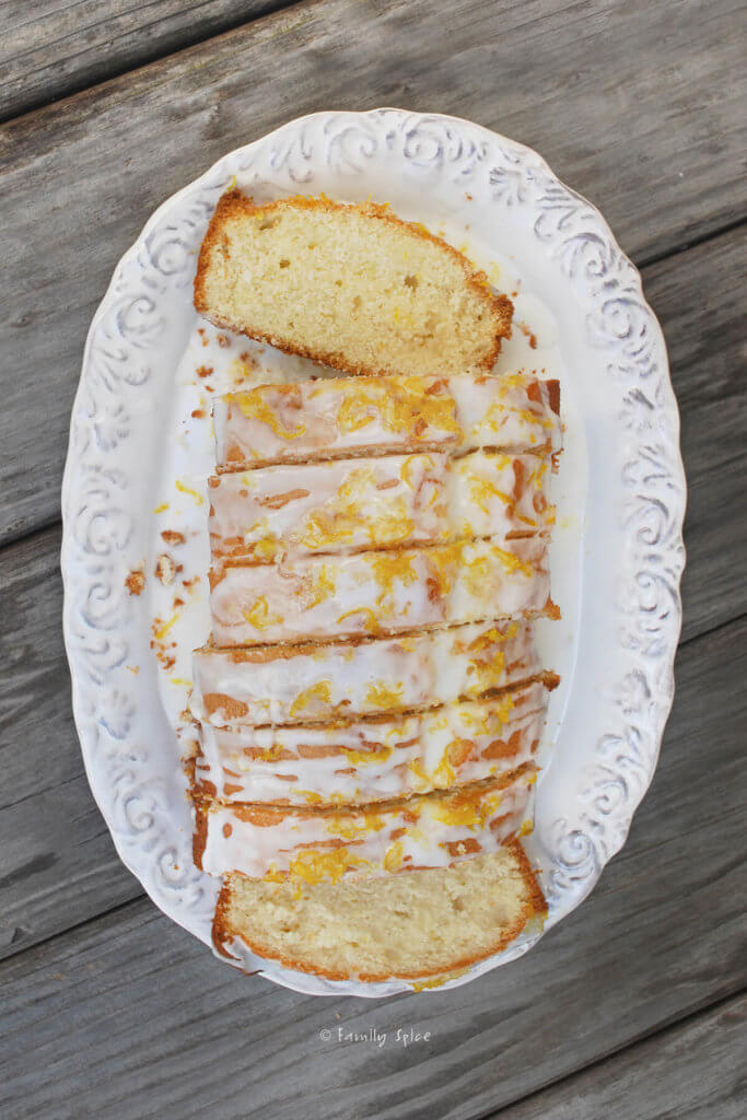Top view of a loaf of lemon tea cake cut into slices onto a white oval platter