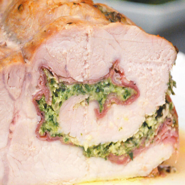 An Italian pork roast rolled and stuffed with pesto and prosciutto on a serving platter