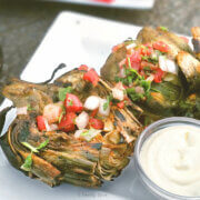 Two artichoke halves grilled and seasoned with chile lime and topped with pico de gallo