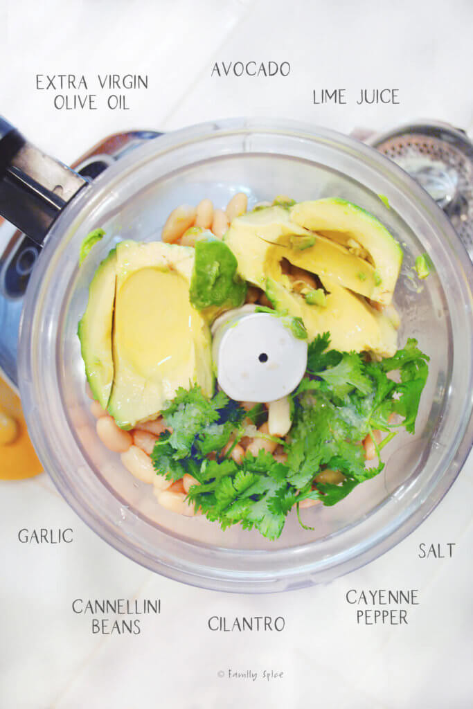 Ingredients needed and labeled to make avocado hummus in a food processor