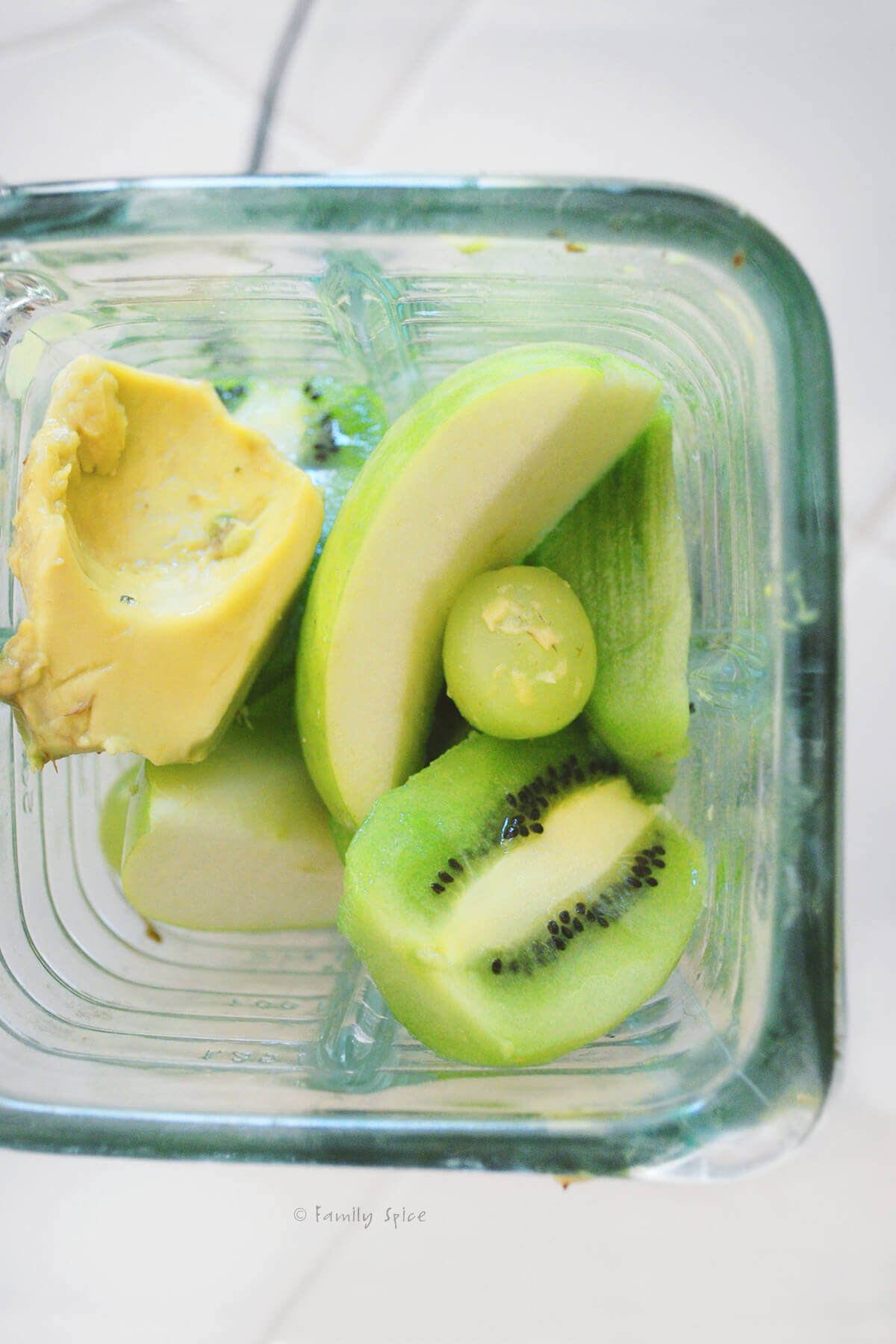 Top view of ingredients in a glass blender needed to make a kiwi smoothie