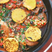 Top view of osso buco in a cast iron dutch oven with browned polenta rounds on top