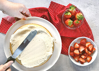Decorating a cake with strawberries next to it