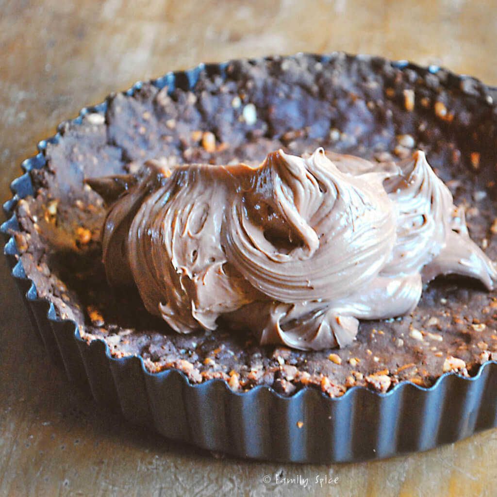 A chocolate pretzel crust pressed into a tart pan with nutella filling dropped inside