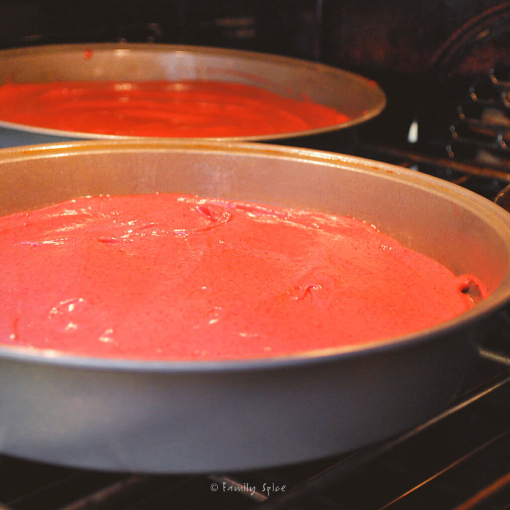 Beet red velvet cake batter in cake pans baking in the oven