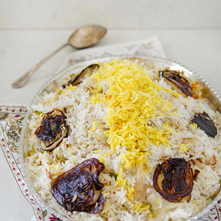 Side view of cabbage rice (kalam polo) with onion tadigh on a silver oval platter