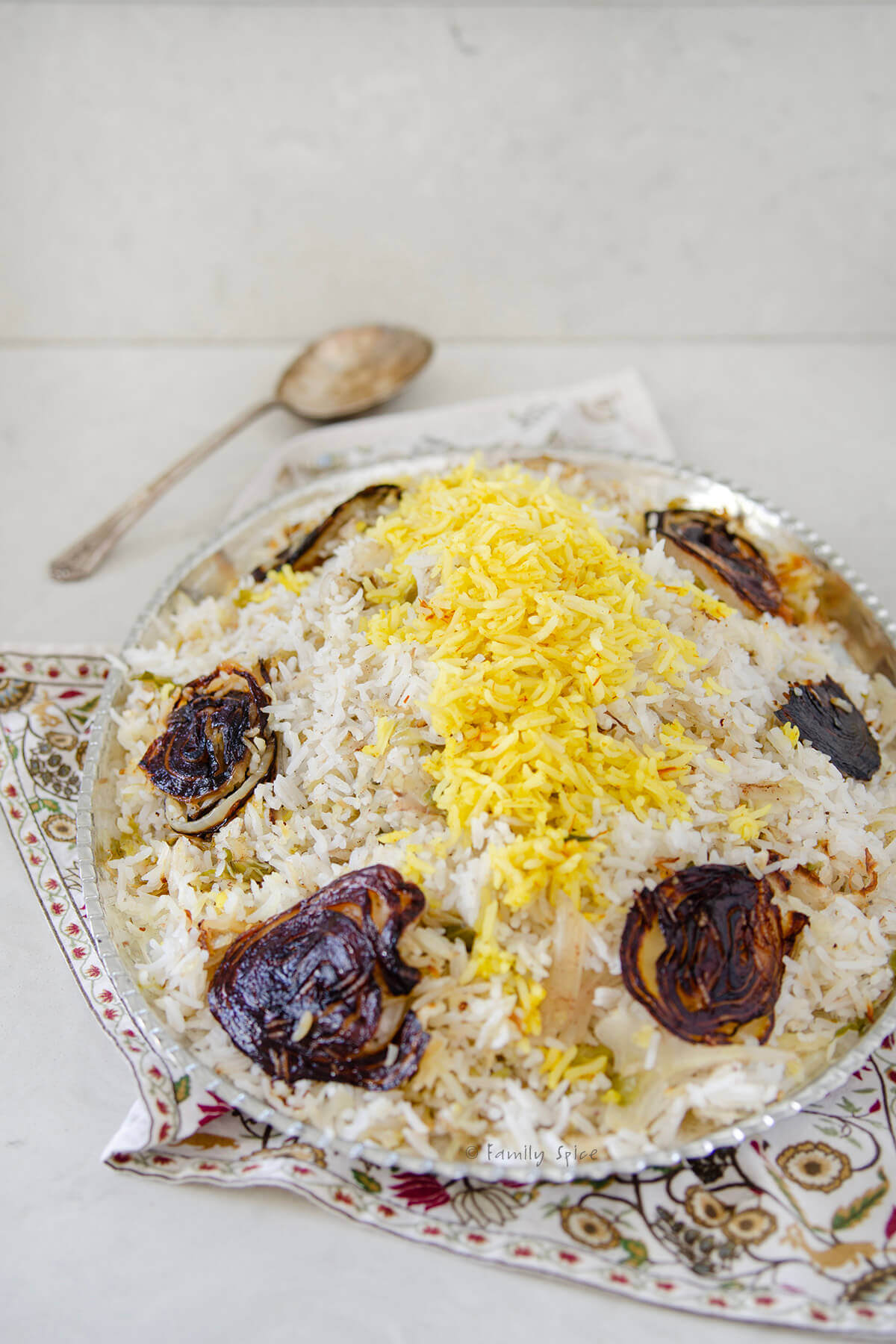 Side view of cabbage rice (kalam polo) with onion tadigh on a silver oval platter