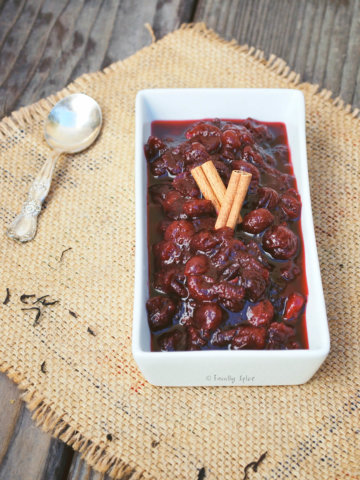A rectangular dish with spiced tea cranberry sauce and cinnamon sticks on top of it