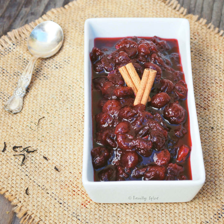 A rectangular dish with spiced tea cranberry sauce and cinnamon sticks on top of it