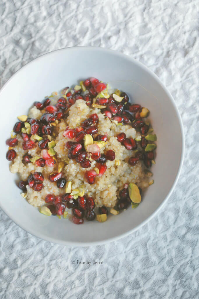 A bowl of breakfast quinoa made with milk and topped with pomegranate and pistachios