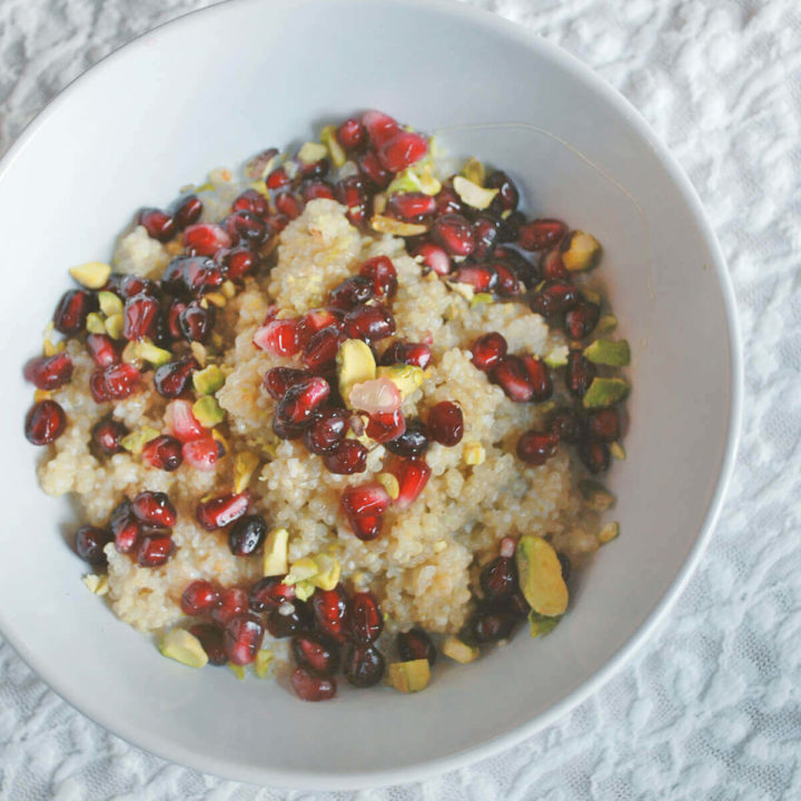 A bowl of breakfast quinoa made with milk and topped with pomegranate and pistachios