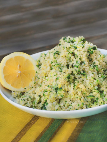 A white bowl with zucchini and lemon quinoa pilaf with a yellow and green napkin
