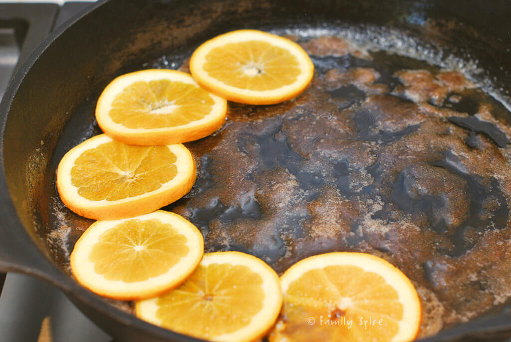 Brown sugar in melted butter in a cast iron pan with a few orange slices on the bottom of it