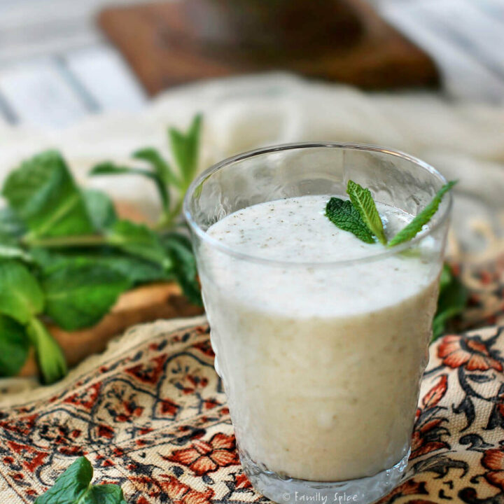 A glass of doogh (persian yogurt drink) with fresh mint next to it