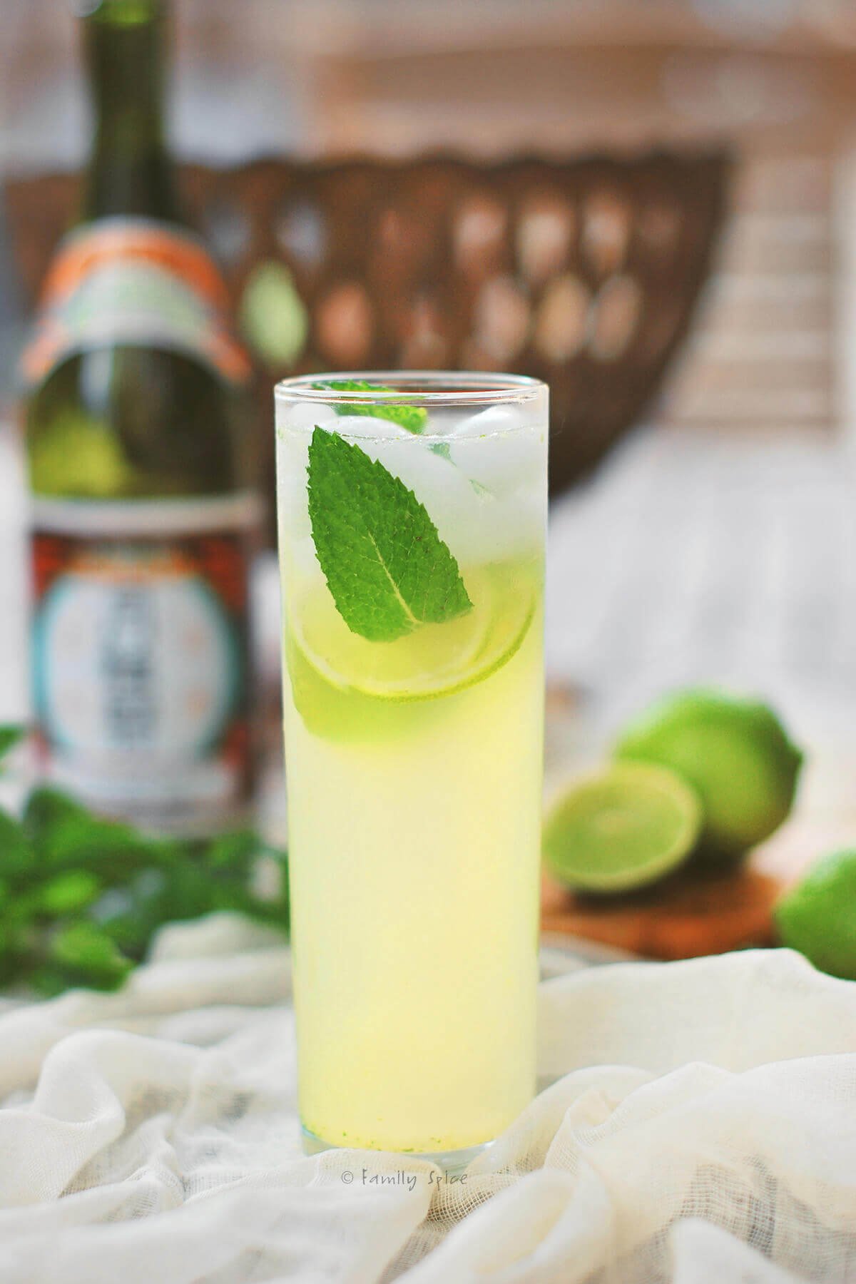 A tall glass filled with a sake mojito garnished with mint and lime.