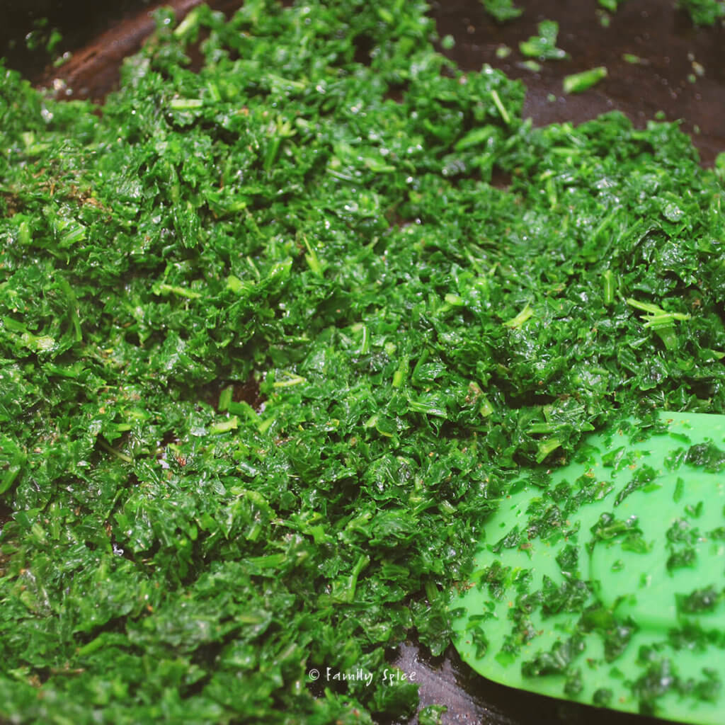 Chopped green herbs getting cooked in a pan