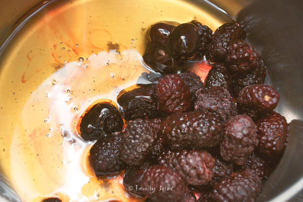 Honey and thawed blackberries in a small stainless pot