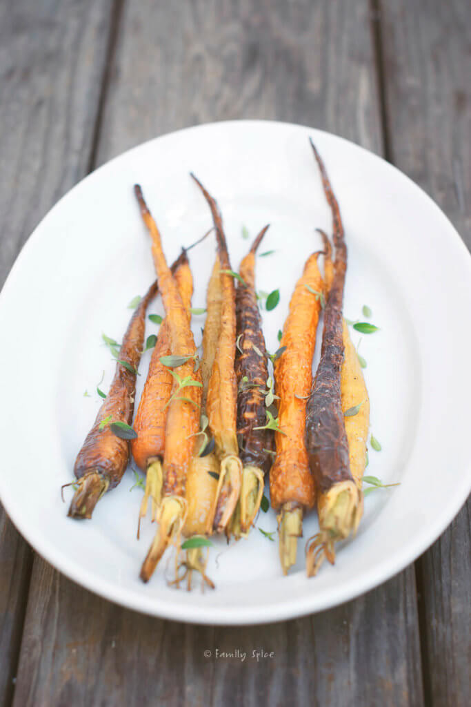 Side view of roasted baby carrots on a white platter