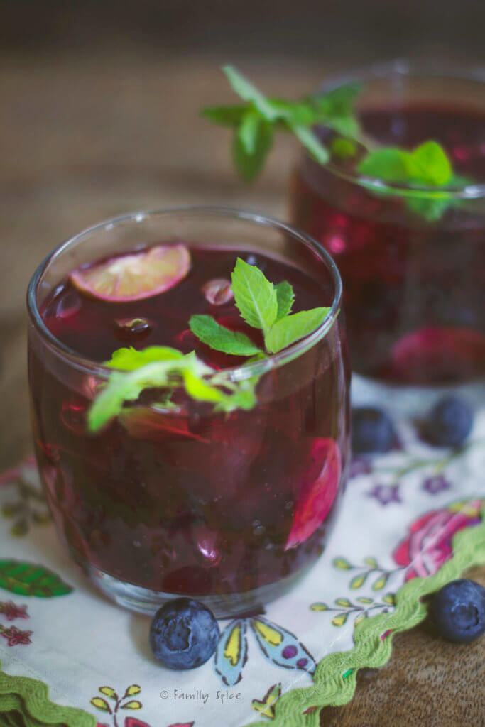 Closeup of two glasses of blueberry mojitos on a floral napkin