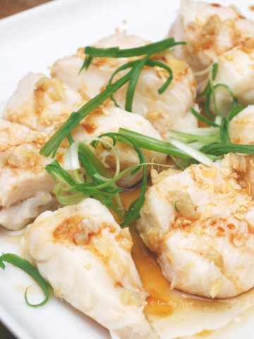 A platter of steamed halibut topped with garlic and chives