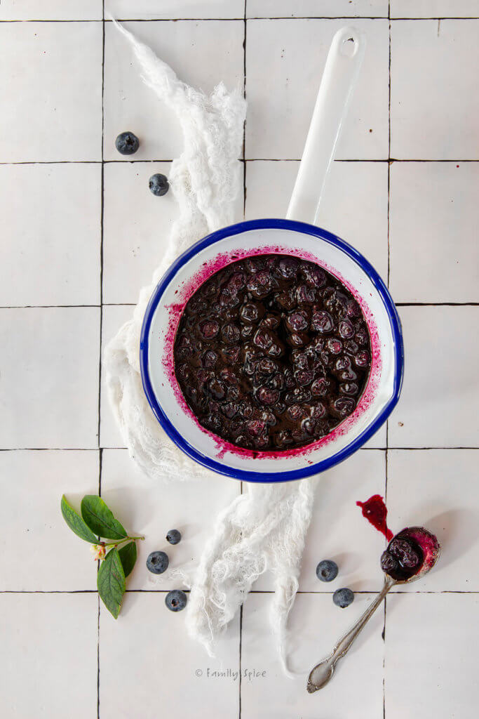 Top view of a white enamel bowl with homemade blueberry preserves in it