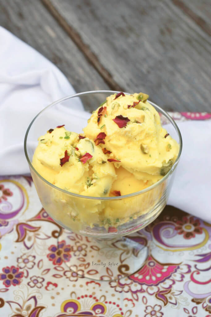 ¾ view of several scoops of Persian ice cream garnished with pistachios and rose petals