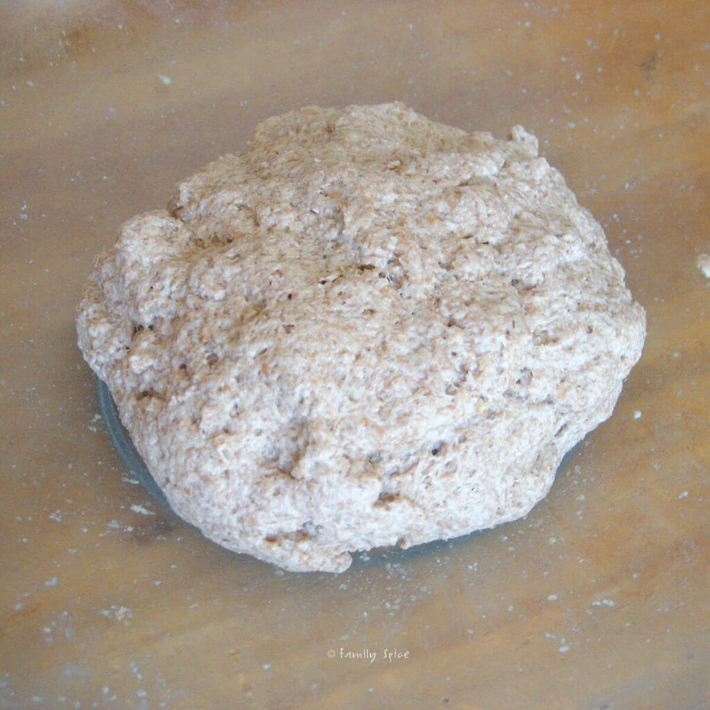 Whole wheat pizza dough kneaded into a ball in a glass bowl