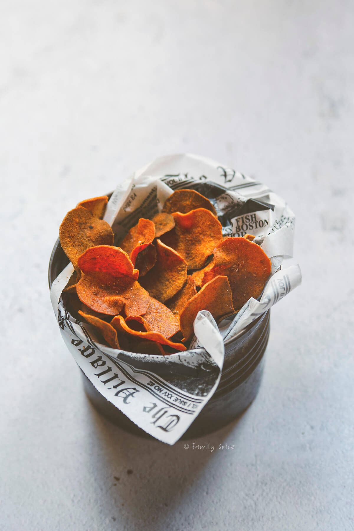 Side view of a metal container filled with baked sweet potato chips