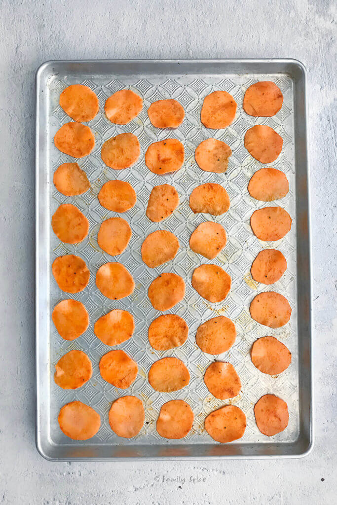 Sweet potato slices oiled and seasoned on a baking sheet ready to be baked