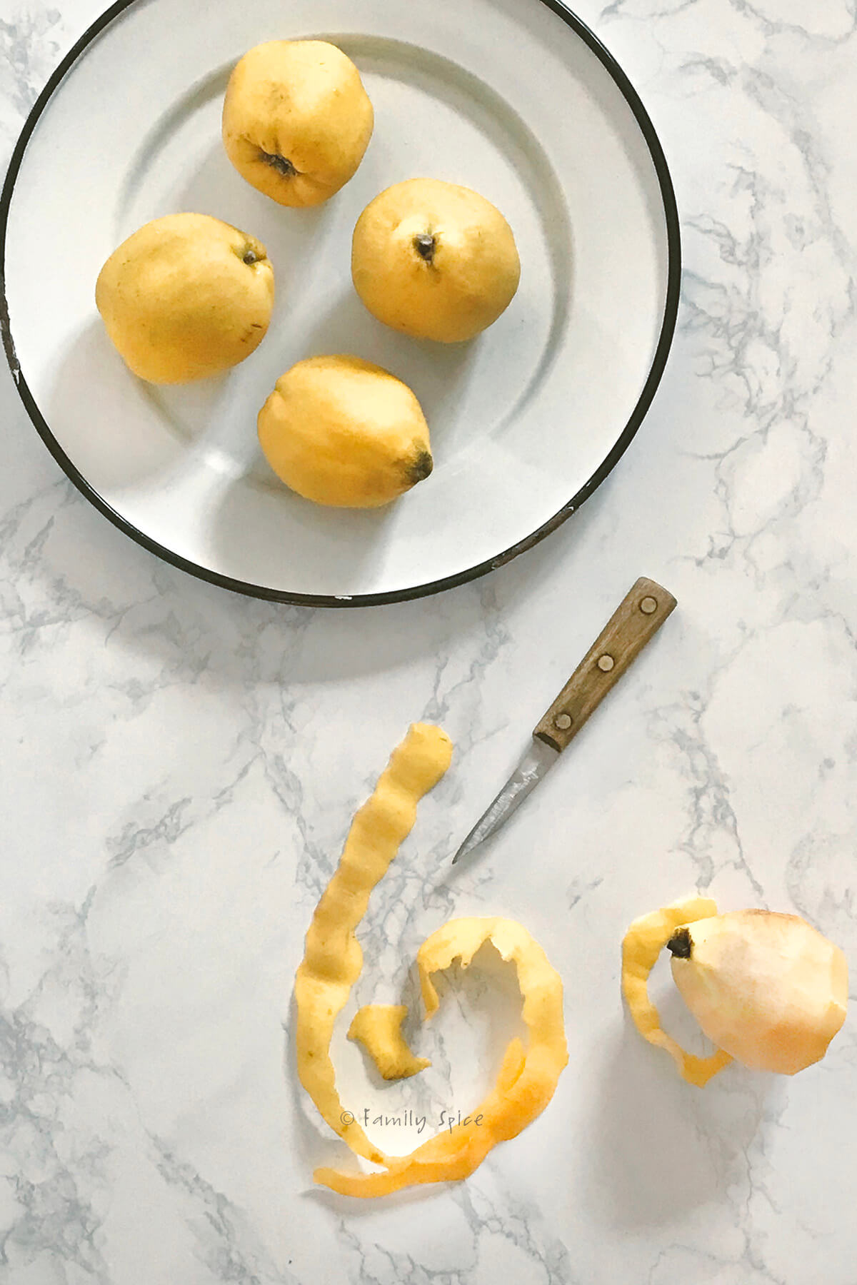 A platter of quince with a pairing knife and peeled quince