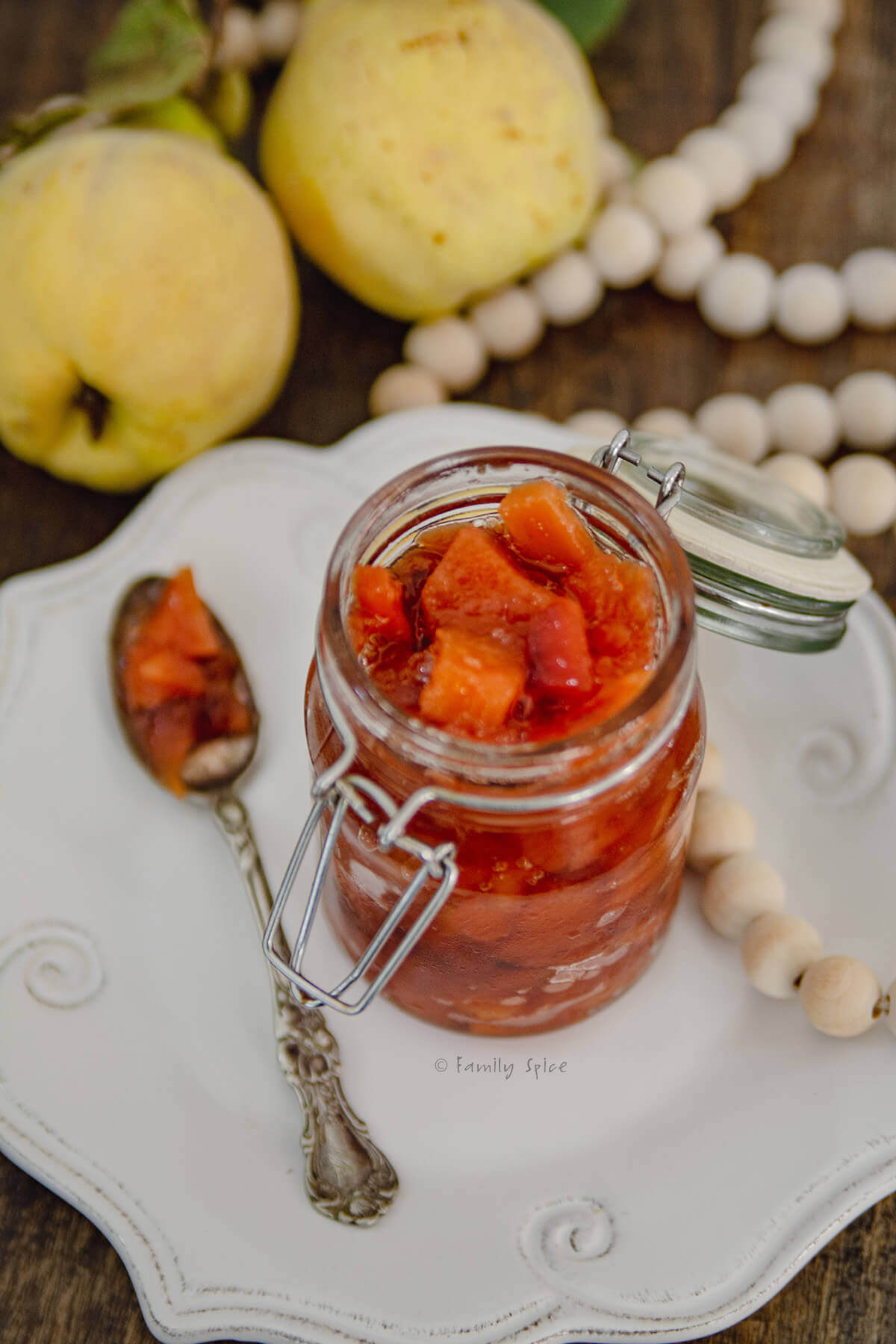 Closeup of a mason jar with red quince jam on a white plate