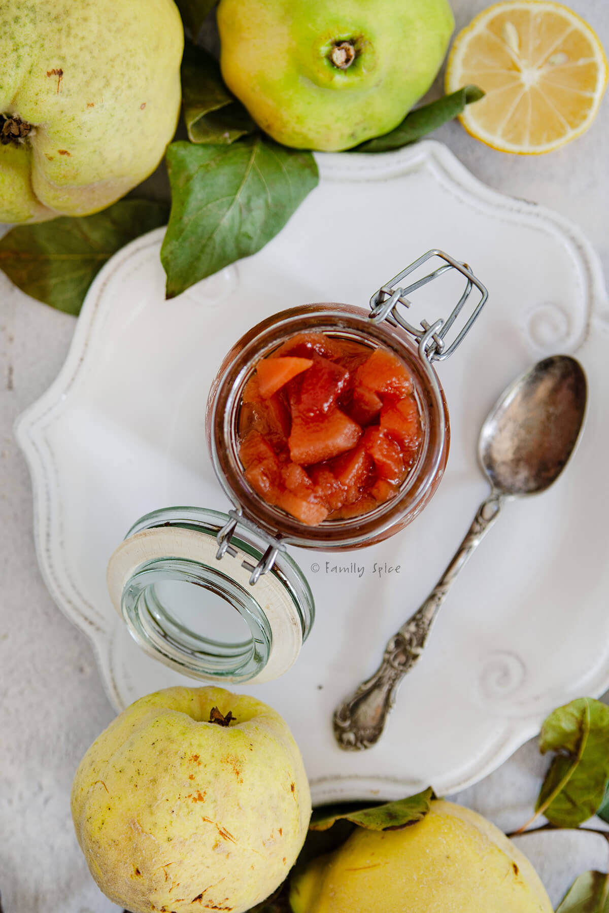 Top view of a mason jar with red quince jam on a white plate