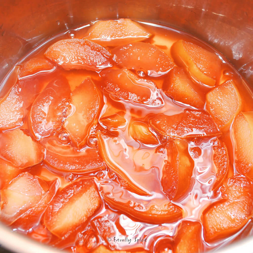 Cooking quince slices in a pot to make jam with color turning orange-pink