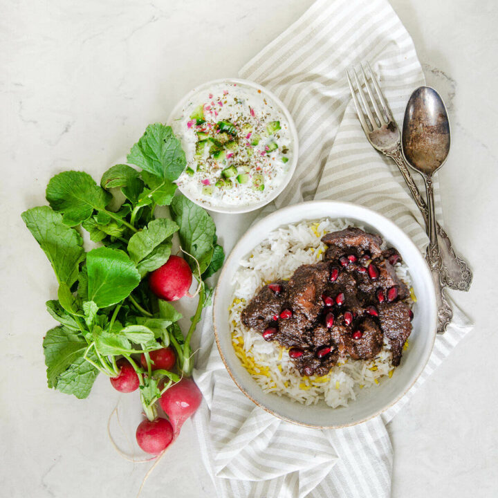 A single serving of white basmati rice topped with fesenjoon, a small bowl with mast o khiar and fresh radishes