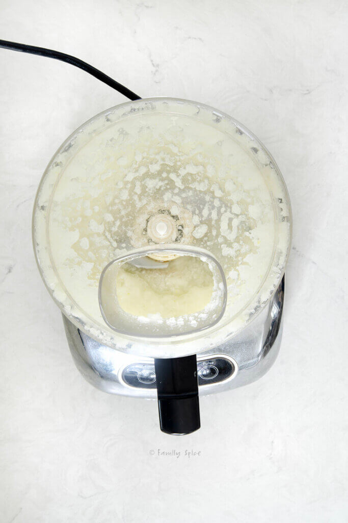 Top view of a food processor with lid and onions getting processed in it