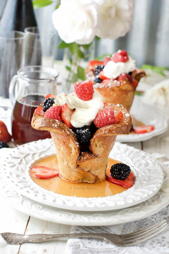 Side view of baked french toast cups filled with berries and whipped cream